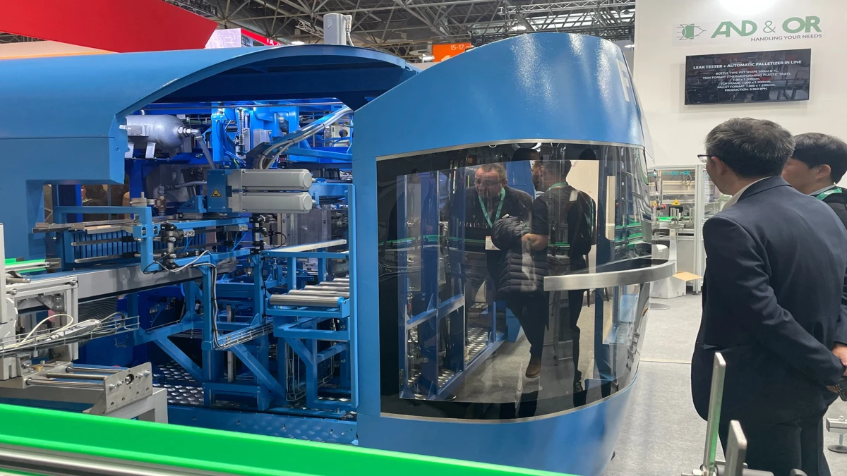 Profissionais analisam equipamento automatizado de alta precisão em exibição na K-Messe Düsseldorf.